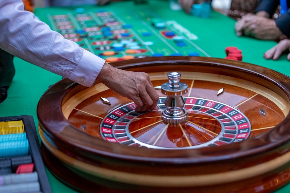 Tangan memutar roda roulette dengan chip di sekitarnya